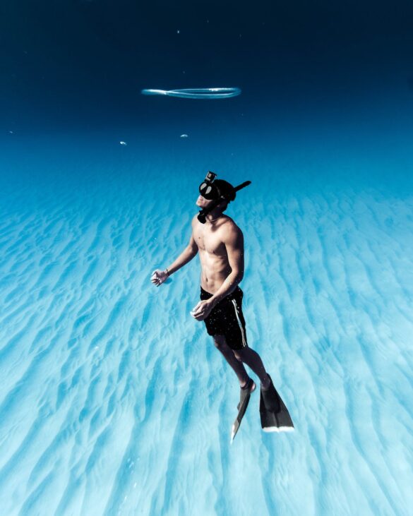 Unrecognizable man snorkeling in azure seawater Unrecognizable man snorkeling in azure seawater
