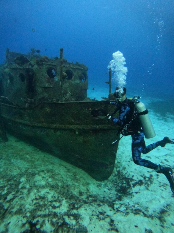 A Scuba Diver Near a Sunken Boat Underwater A Scuba Diver Near a Sunken Boat Underwater