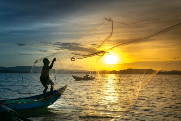 Man Standing On Boat Throwing Net Man Standing On Boat Throwing Net