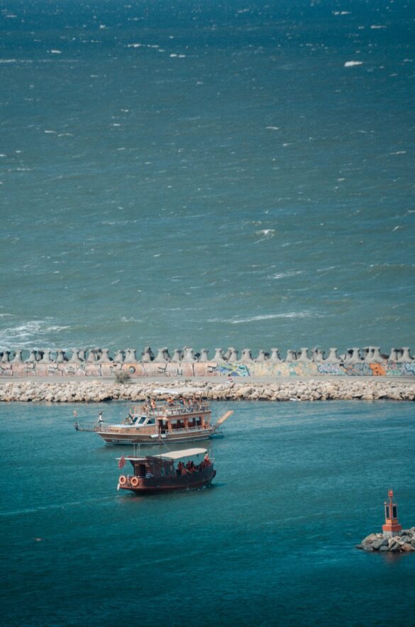 free-photo-of-traditional-boat-sailing-near-rocky-sea-barrier Svg%3E
